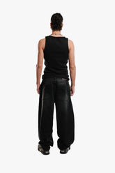 A person standing  wearing a black sleeveless top and black pants.