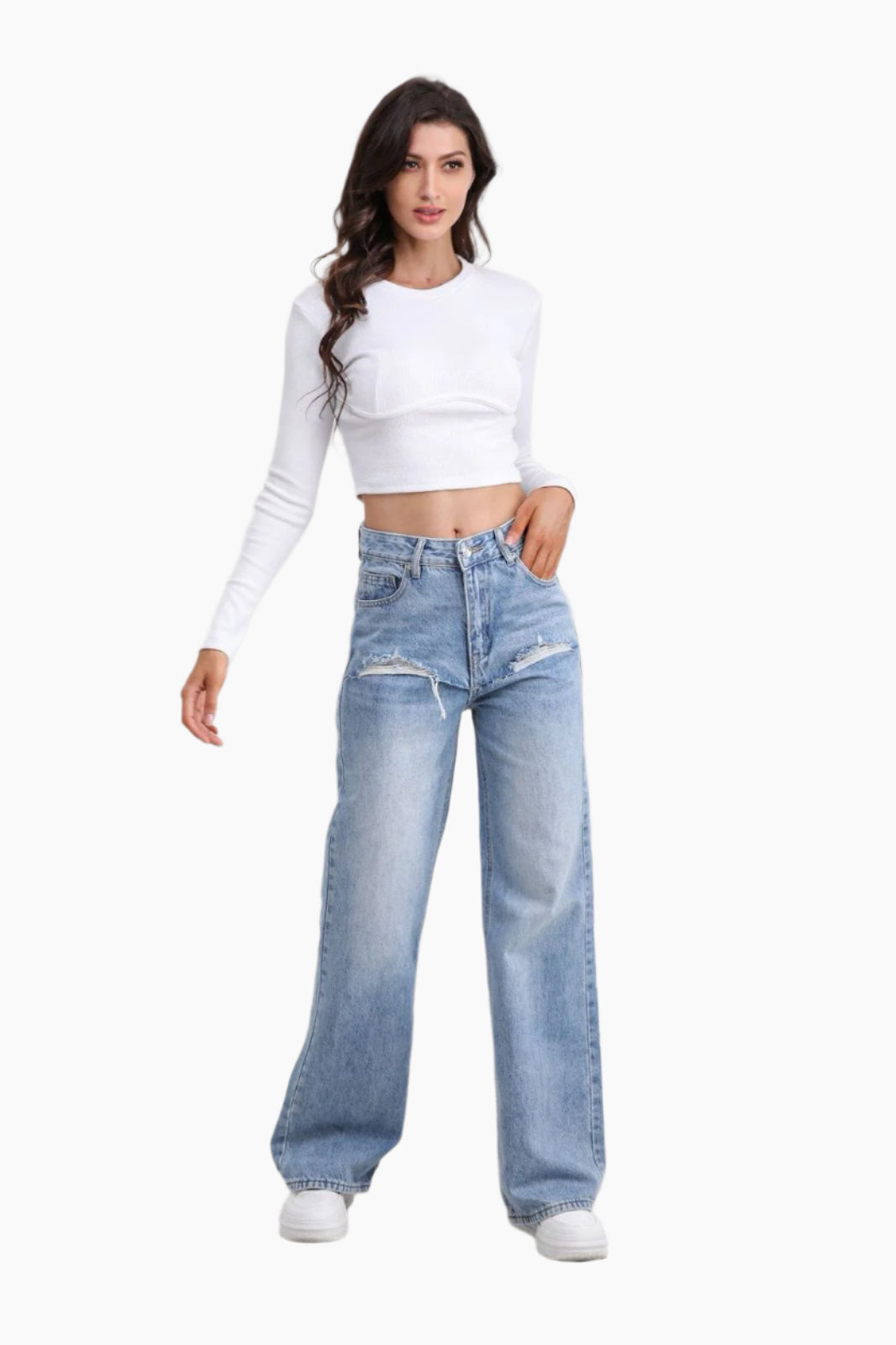 Woman wearing a white long-sleeve crop top and light blue jeans 