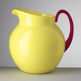 Yellow pitcher with a red handle on a gray background