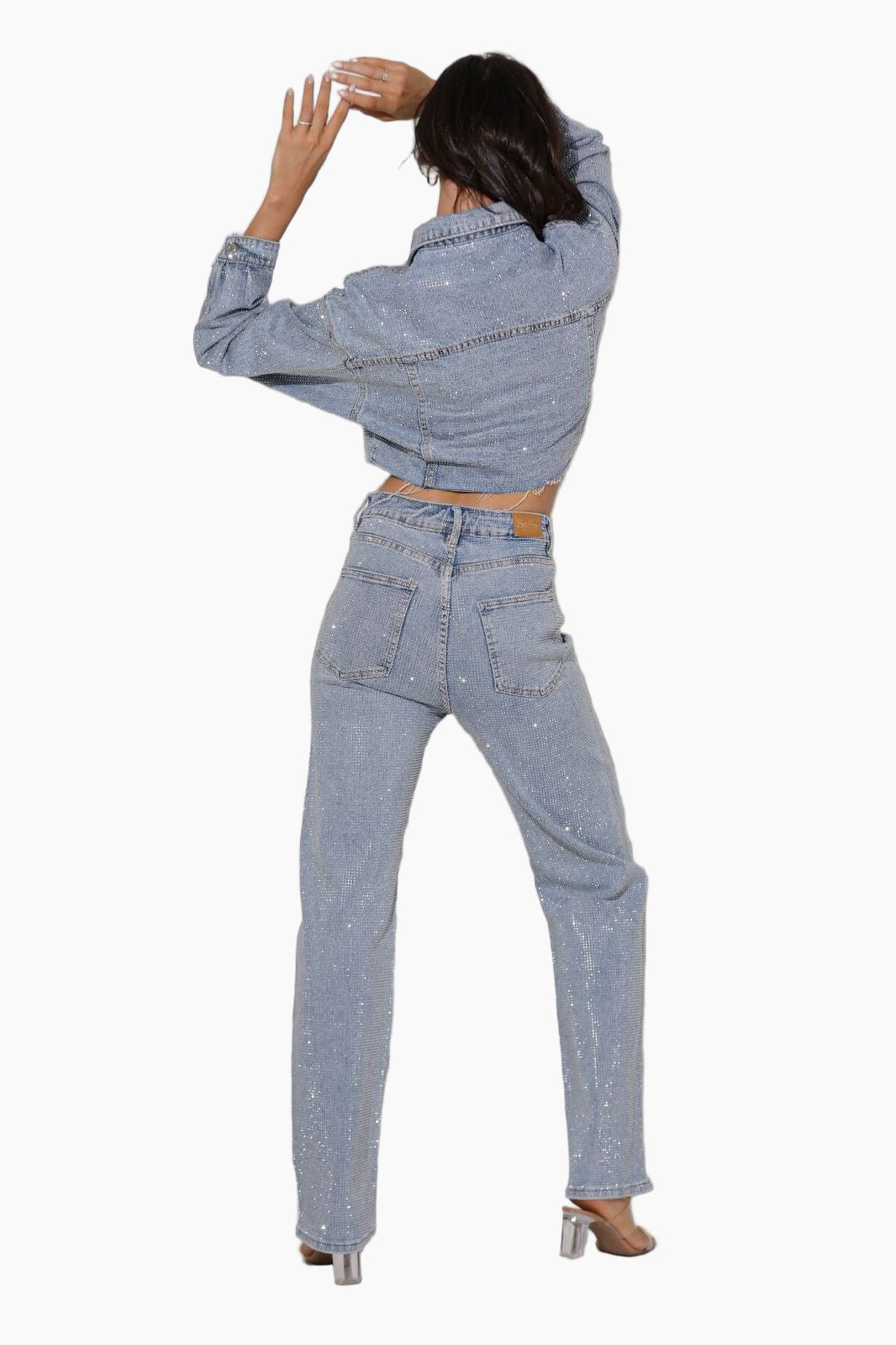 Person wearing a matching denim jacket and jeans set on a white background