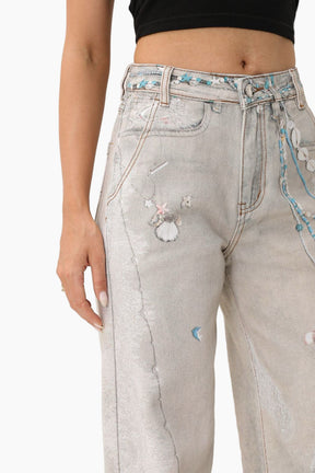 Light gray jeans with decorative elements worn by a person 