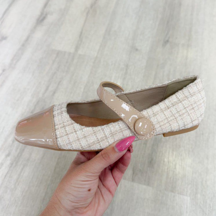 Beige and white shoe with a strap held by a hand