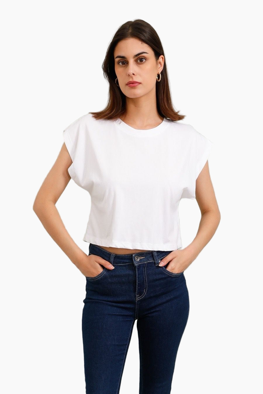 Woman wearing a white crop top and dark blue jeans 