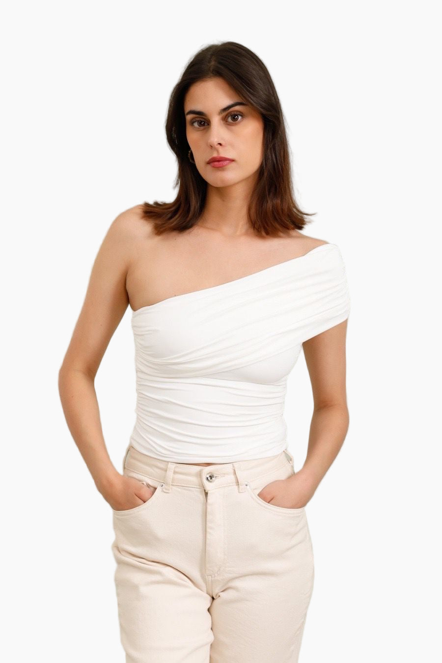 Woman wearing a white one-shoulder top and beige pants 