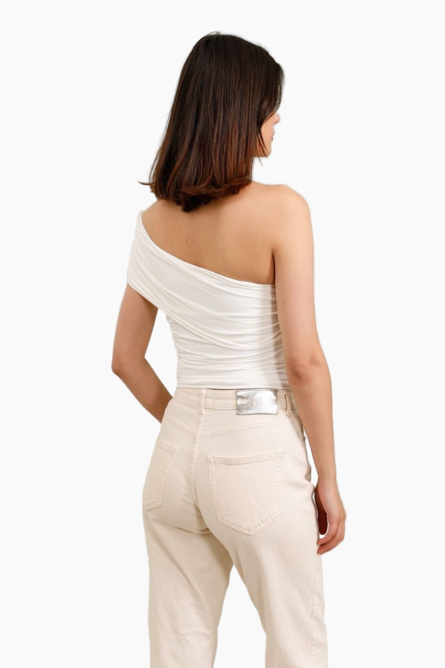 Woman wearing a white one-shoulder top and beige pants 