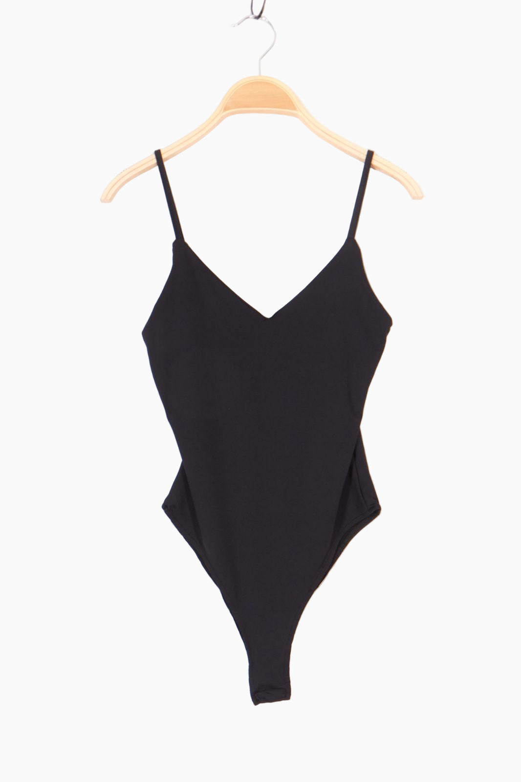 Black bodysuit on a wooden hanger against a white background