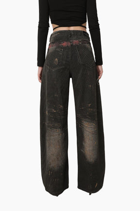 Person wearing dark distressed jeans =