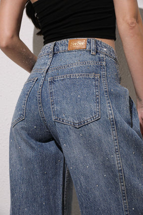 Person wearing blue jeans with a visible brand label 