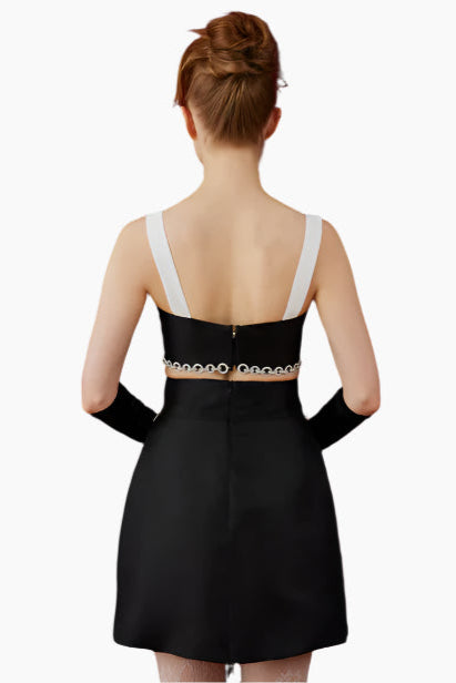 Model wearing a black and white outfit, crop top and skirt with chain with long gloves 