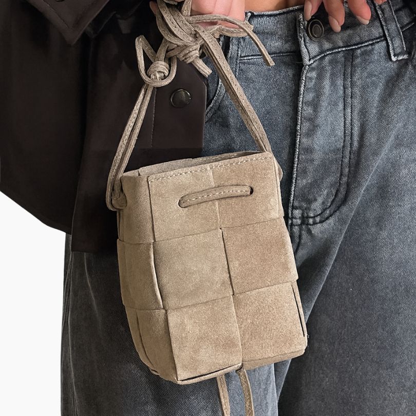 Beige patchwork bag held by a person wearing jeans and a dark coat.