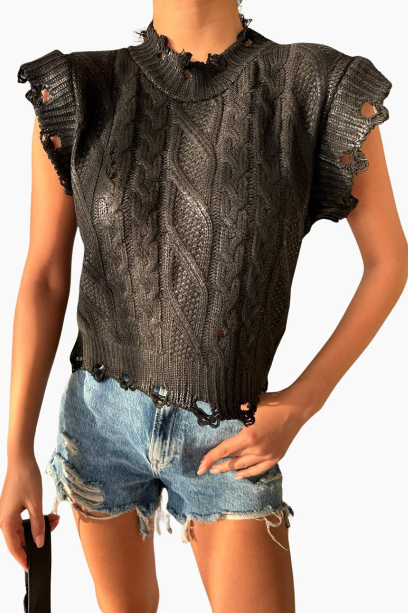 Person wearing a black knit top with distressed details and denim shorts 