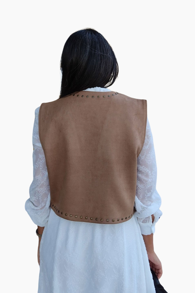 Person wearing a brown vest over a white shirt and dress