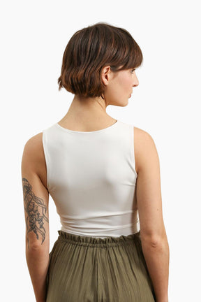 Woman wearing a white sleeveless top and green skirt on a white background