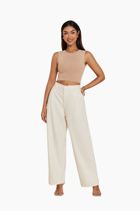 Woman wearing a beige sleeveless top and white pants 