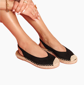 Black espadrille shoes with gold trim worn by a person 