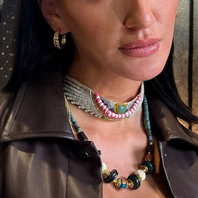Close-up of a woman wearing multiple necklaces and hoop earrings.