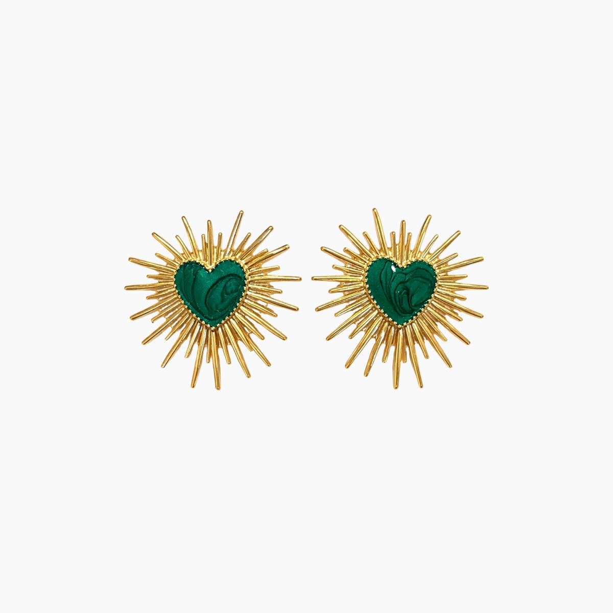Pair of earrings with gold sunburst design and green heart center on a white background