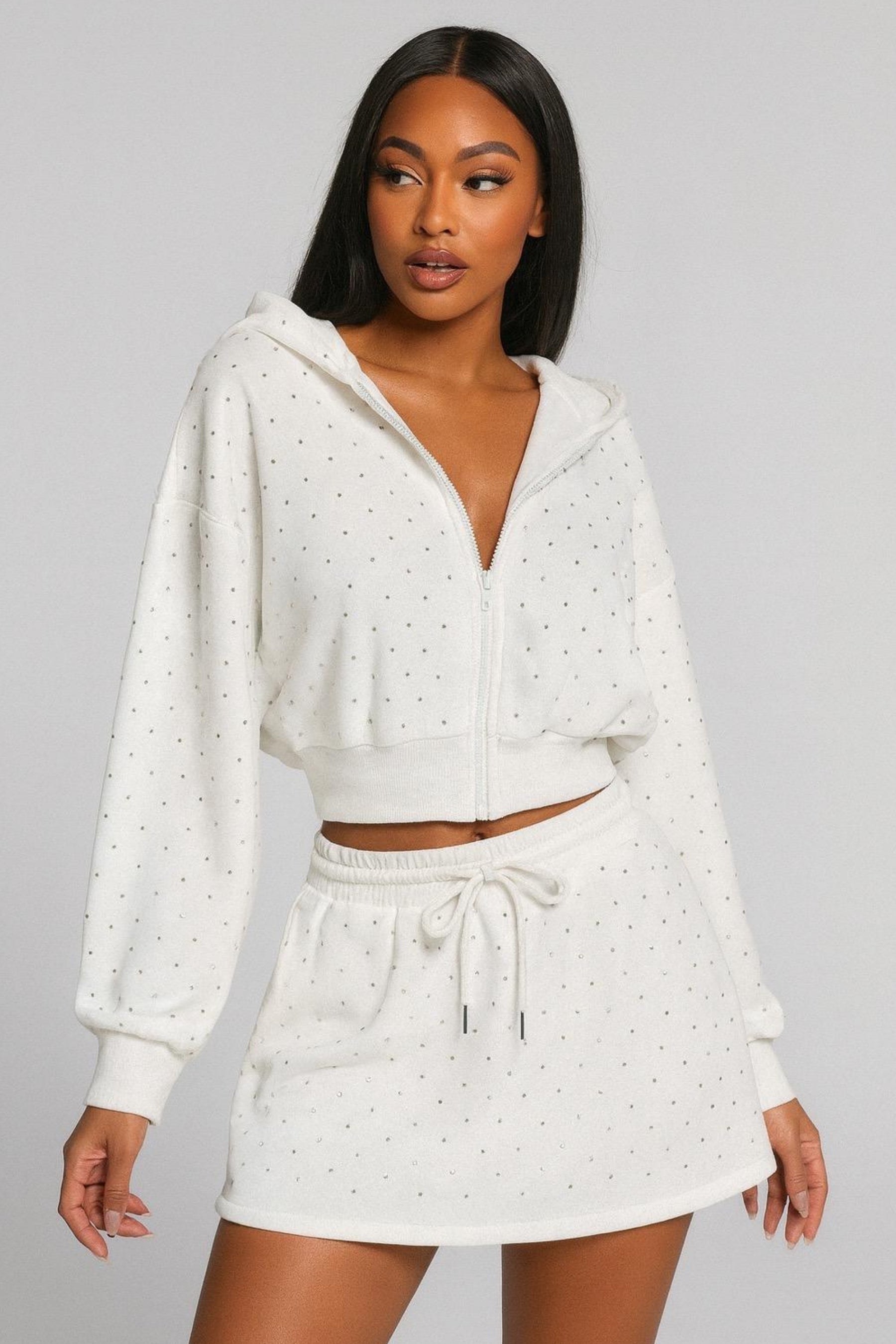 Woman wearing a white polka dot hoodie and skirt set on a gray background