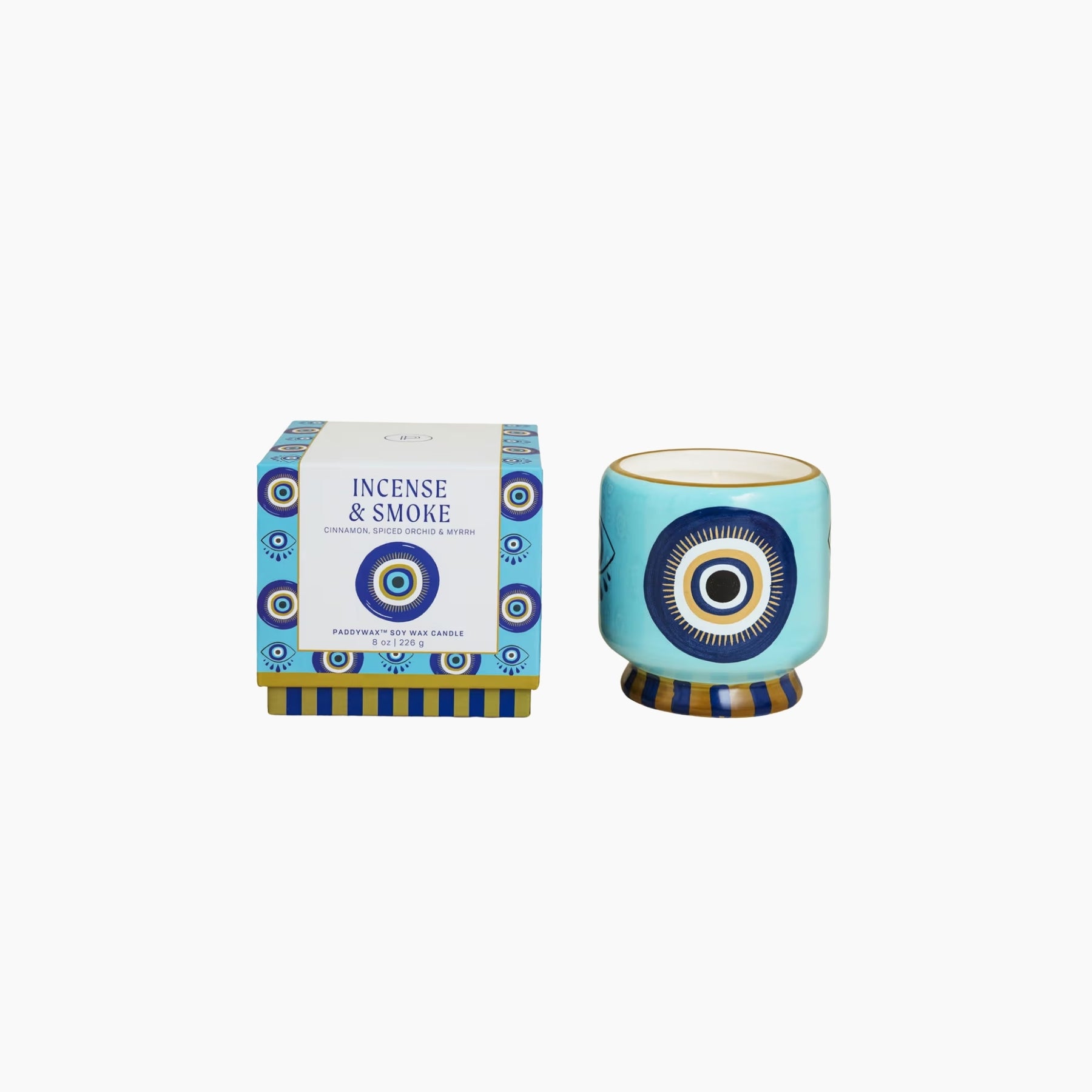 Decorative candle with blue and white design next to its packaging on a white background