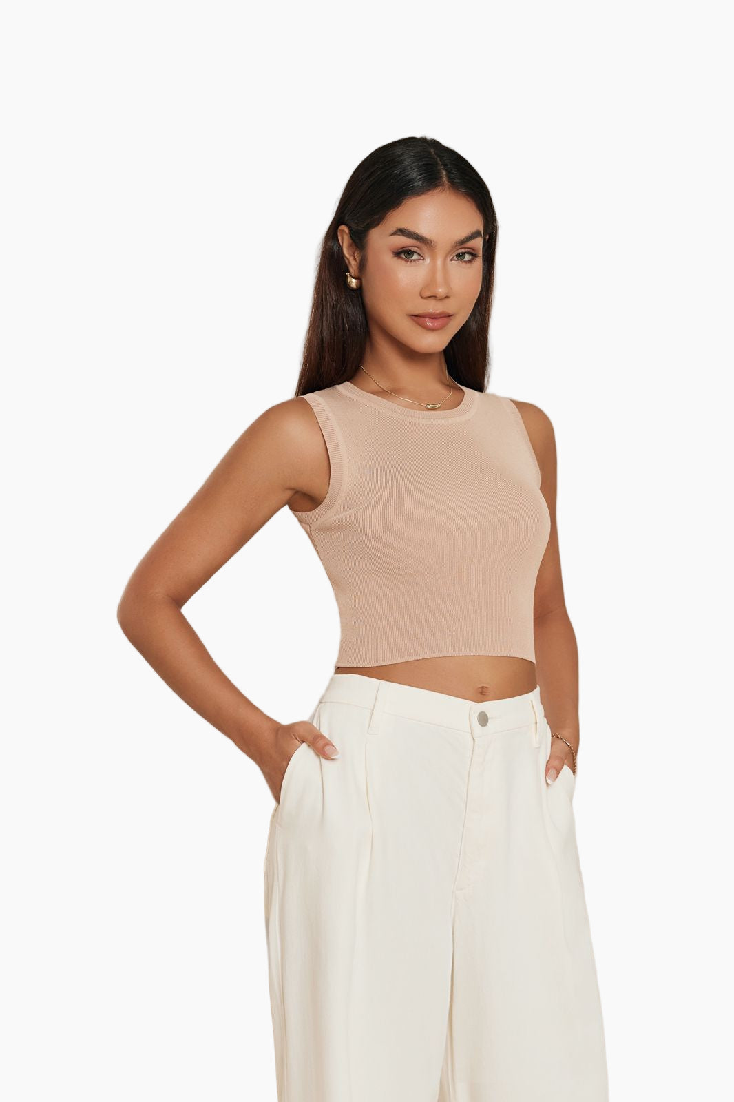 Woman wearing a beige sleeveless top and white pants 