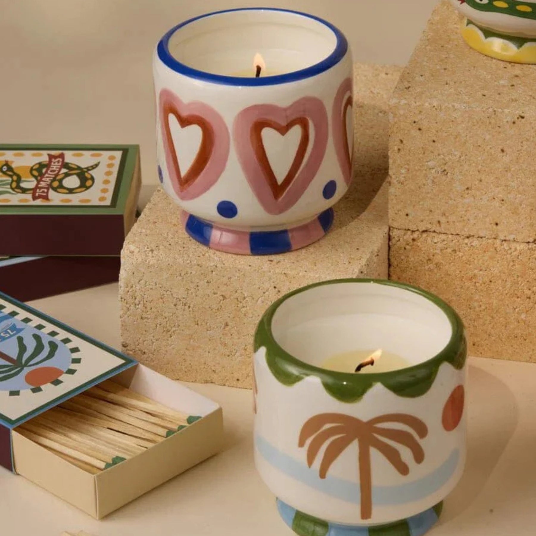 Two ceramic candles with decorative patterns on a surface with matches.