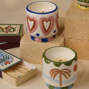 Two ceramic candles with decorative patterns on a surface with matches.