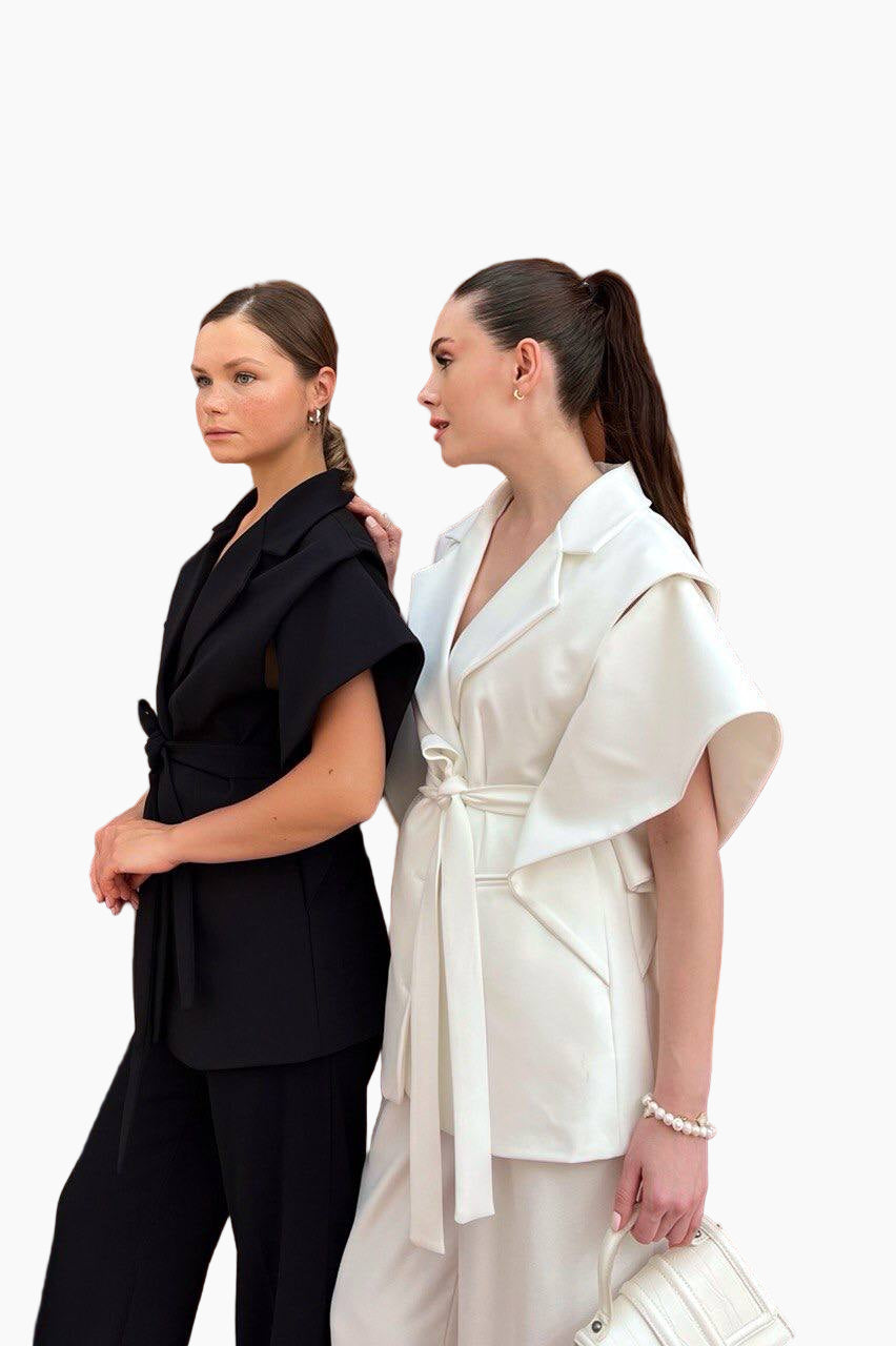 Two women wearing black and white outfits standing back-to-back on a white background