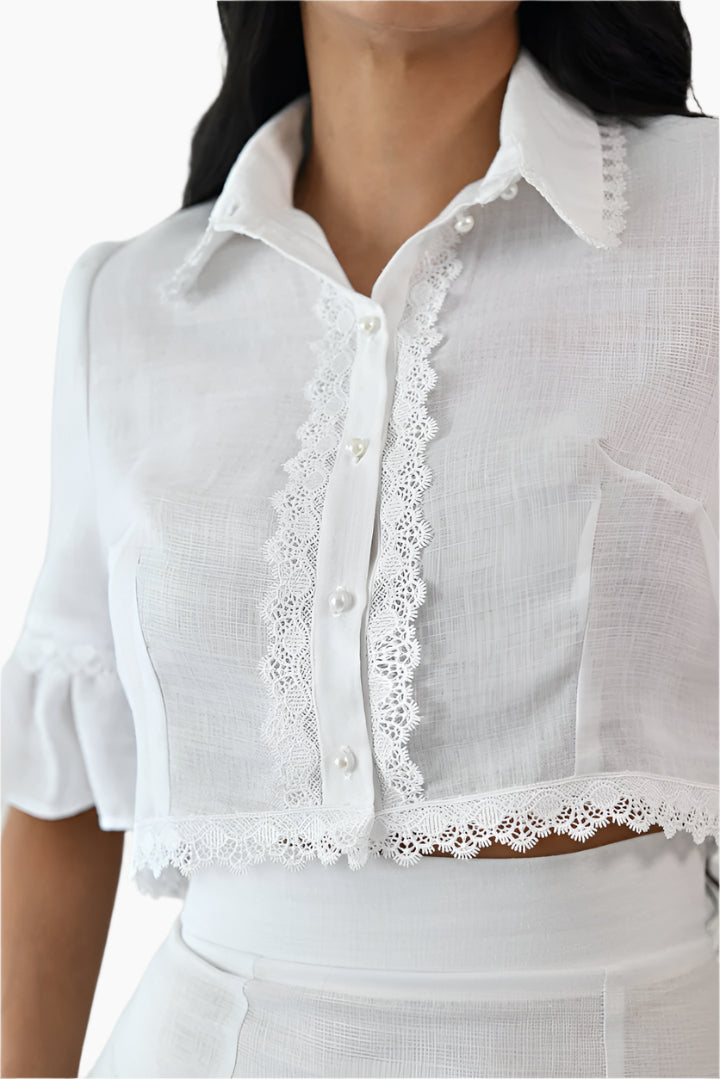  linen blouse it features pearl button fastenings and delicate lace details along the collar, sleeves, and front 