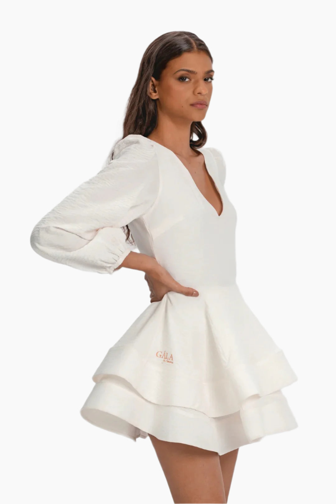 Woman wearing a white dress with long sleeves, soft linen fabric, invisible zipper fastening at the back.