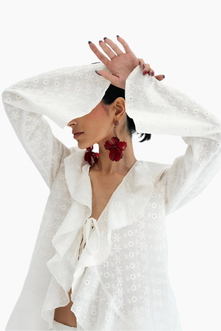 Woman wearing a white embroidered outfit with red earrings 