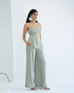 Woman wearing a green and white striped strapless top and wide-leg pants