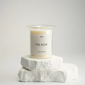 Candle labeled 'Fig Noir' by 'pluto.' on a white background