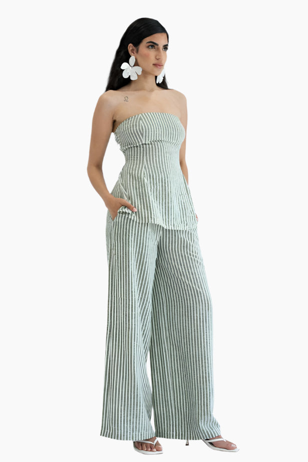 Woman wearing a green and white striped strapless top and wide-leg pants 