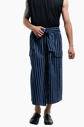 Man wearing a black sleeveless shirt and blue striped pants on a white background