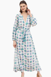 Woman wearing a floral white and blue dress with a tinny belt from the same fabric with tassels 