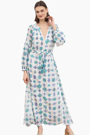 Woman wearing a floral white and blue dress with a tinny belt from the same fabric with tassels 