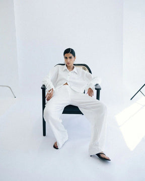 Person wearing a white outfit sitting on a chair