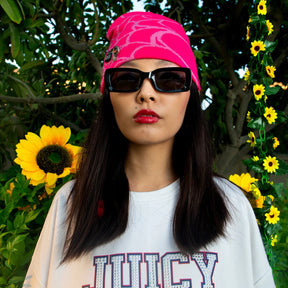 Person wearing a pink headband and a black sunglass with sunflowers in the background