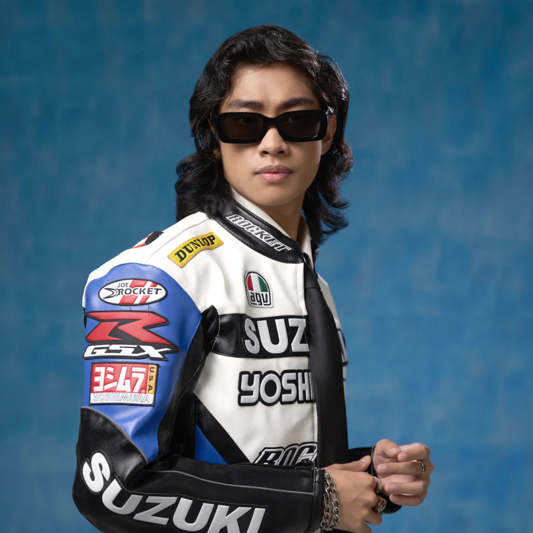 Person wearing a Suzuki racing suit with various sponsor logos paired with a black sunglass 