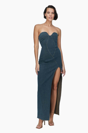 Woman wearing a strapless teal gown with a high slit 