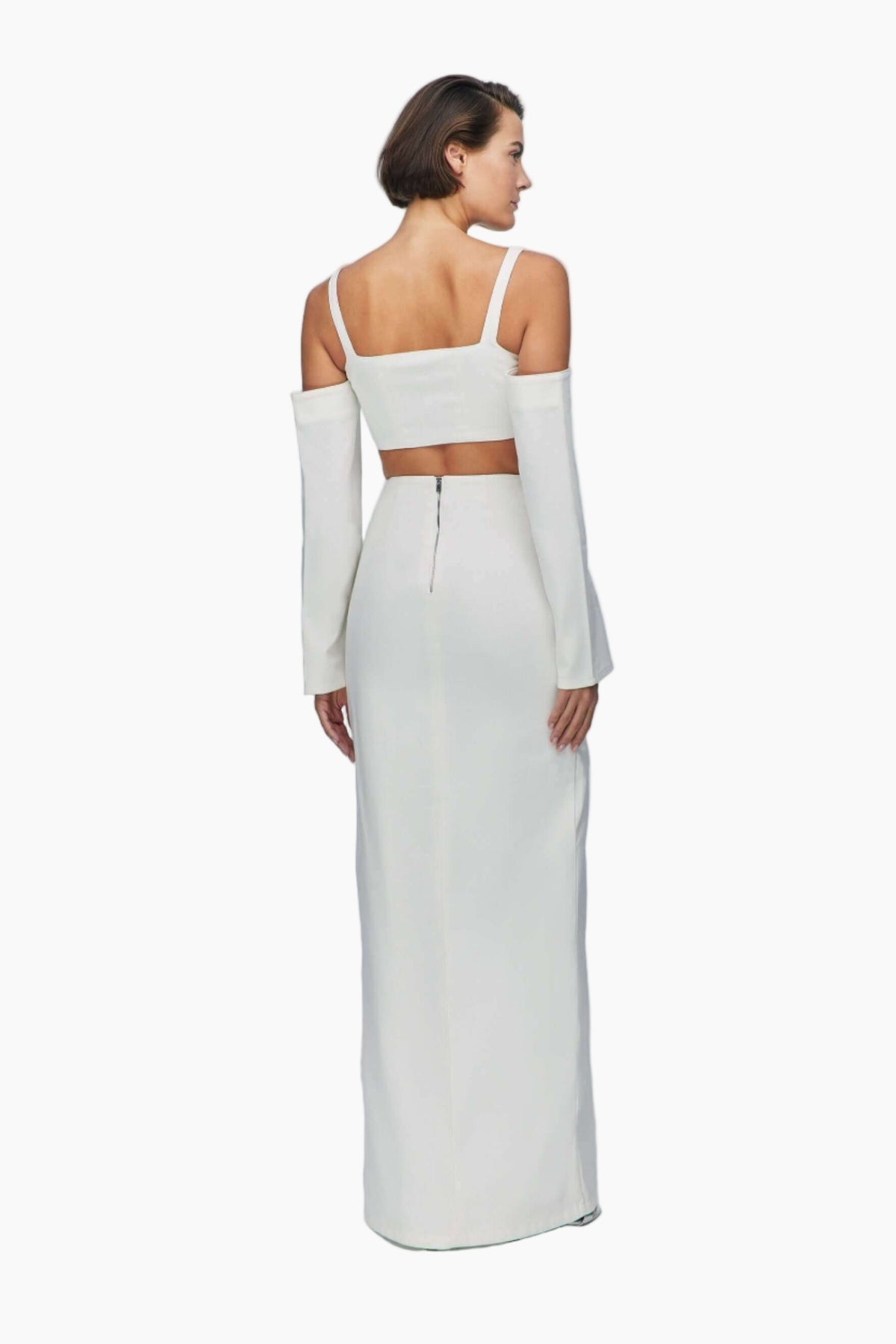 Woman wearing a white top and a maxi skirt features an asymmetric waist and a stylish side slit. 