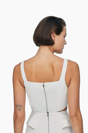 Woman wearing a white sleeveless top with cut-out design 