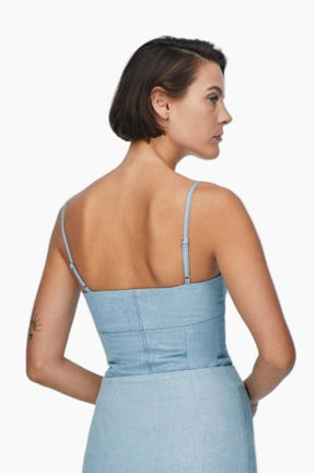 Woman wearing a nesta blue denim, this top feature sultry bustier neckline and chic corset shape
