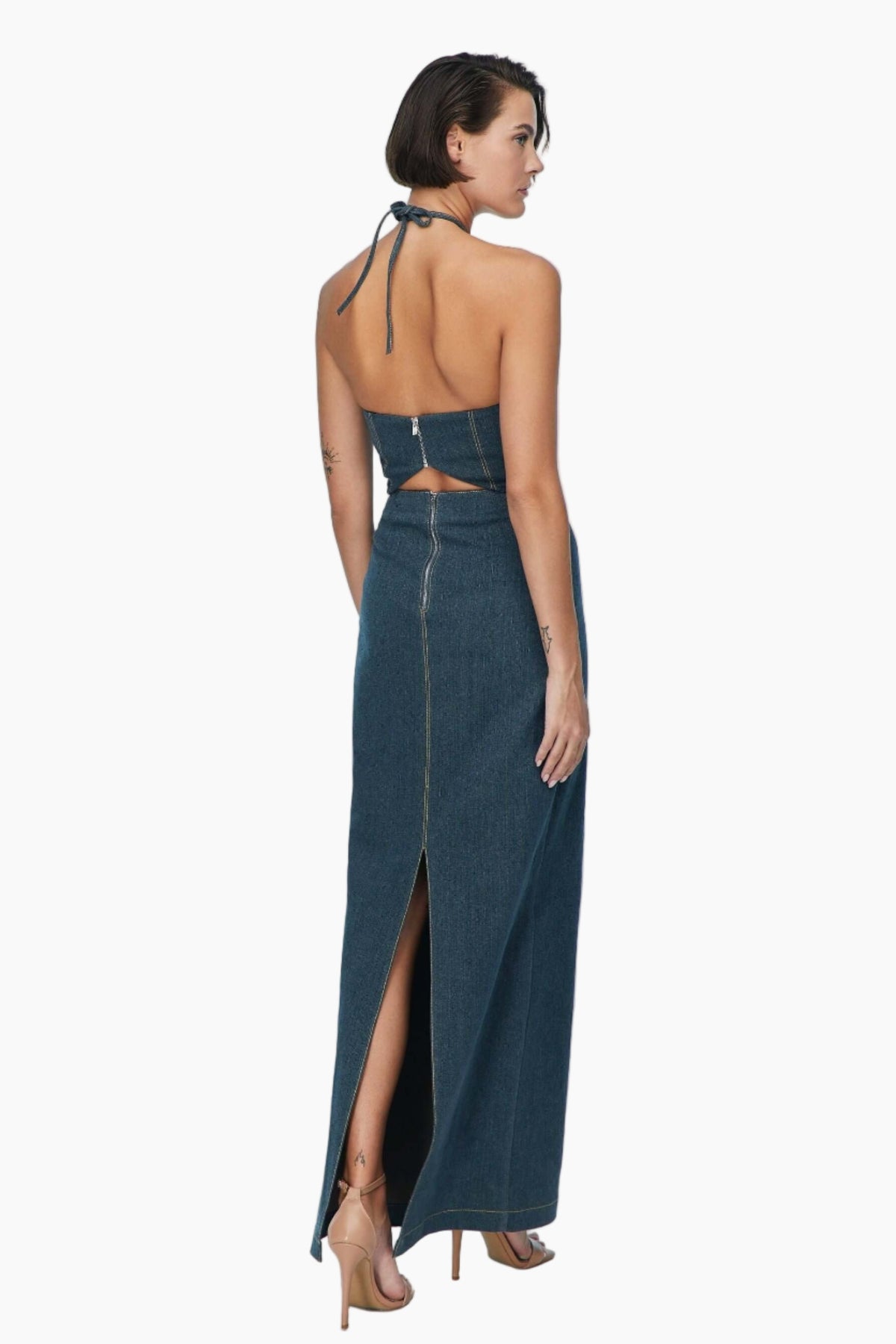 Woman wearing a denim dress with cut-out back and high slit 