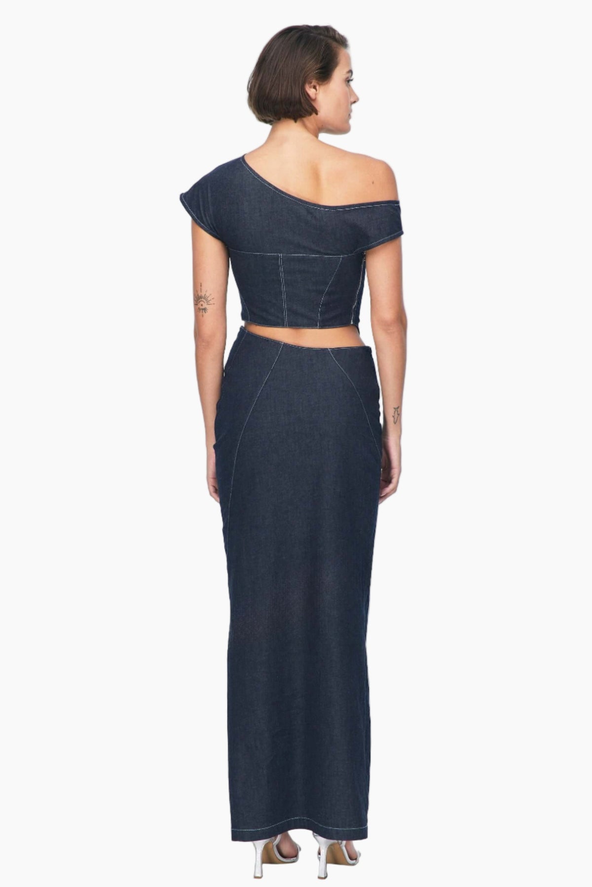 Woman wearing a dark blue off-shoulder top with a Vonk denim skirt features a mid-rise asymmetrical waist. One side slit.