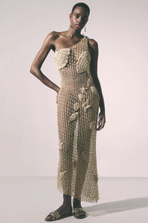 Woman wearing a beige crochet dress on a plain background