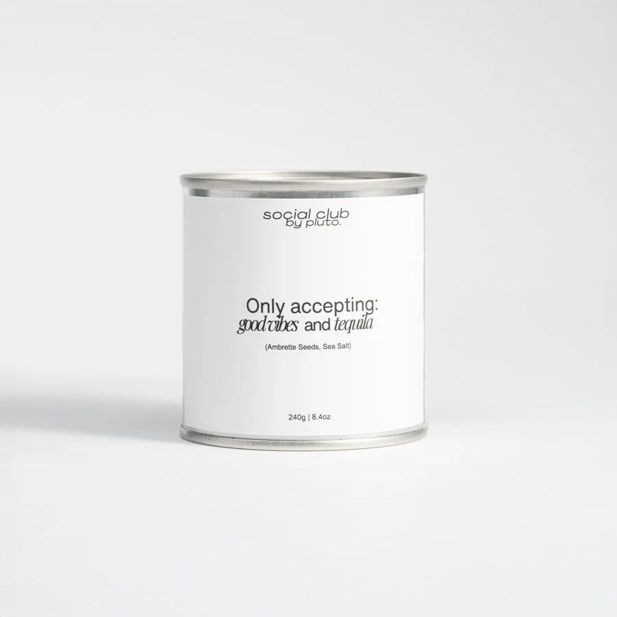 Candle in a tin labeled 'social club by pacco' with humorous text on a white background