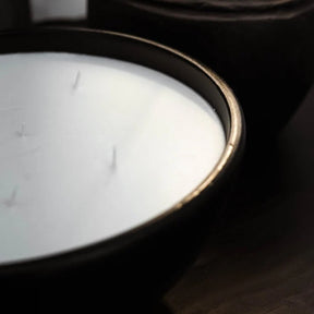 Close-up of a white candle in a black holder on a wooden surface