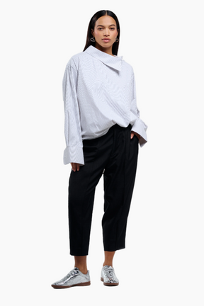 Person wearing a light blue shirt and black pants on a white background