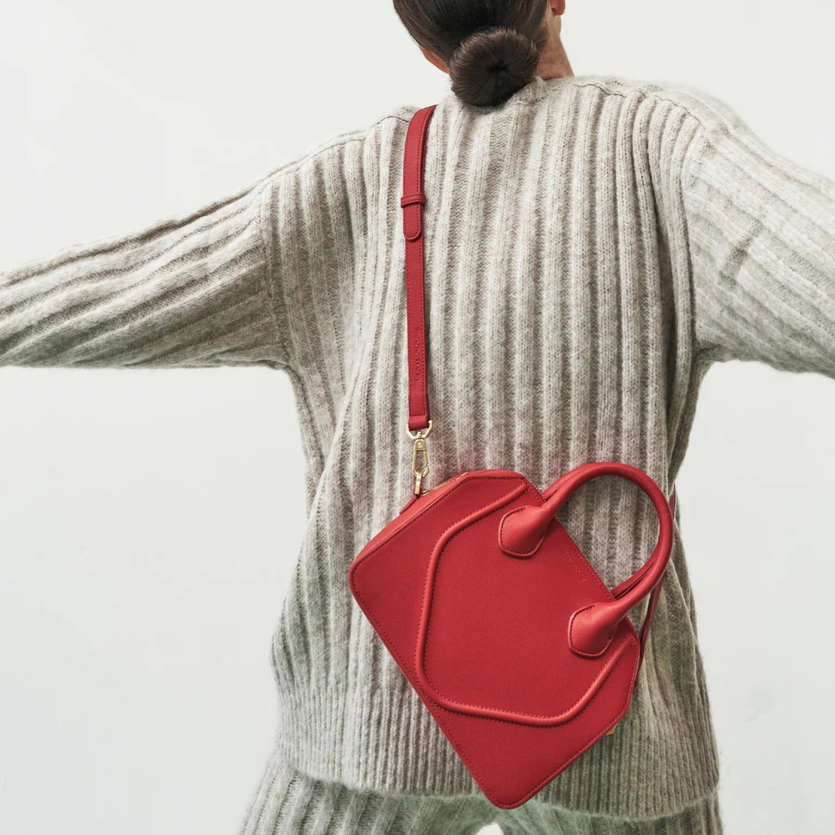 Person wearing a red bag over their shoulder against a light background